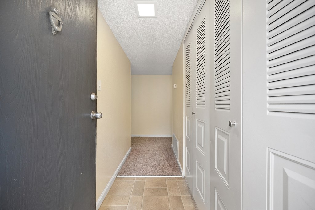 an empty hallway with a closet and a door to a bathroom