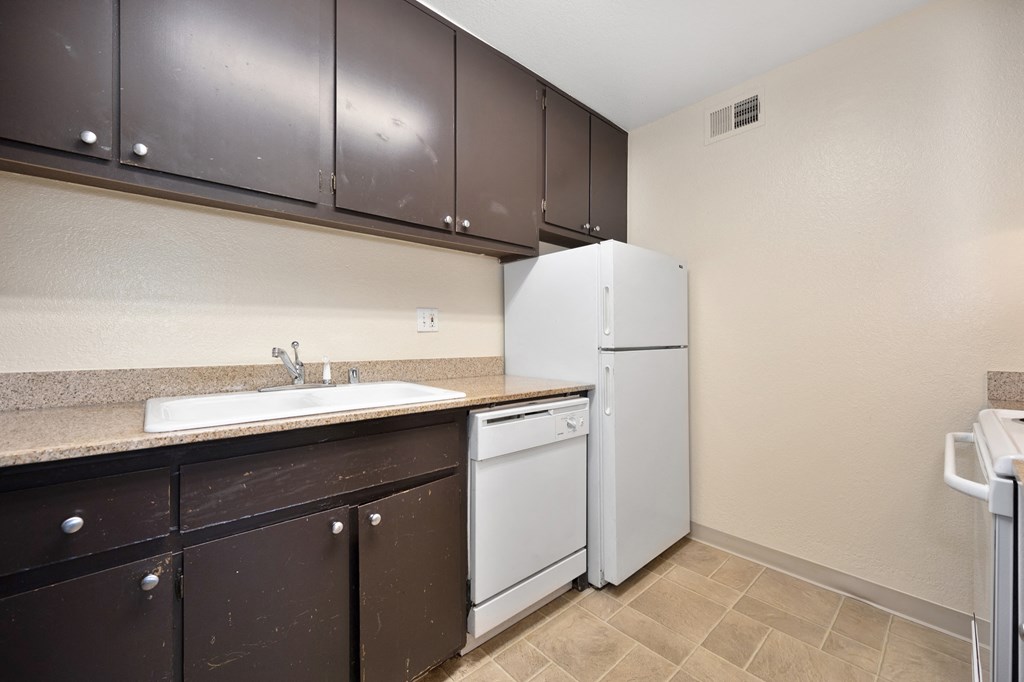 redesigned kitchen with white appliances and dark cabinets and a white refrigerator