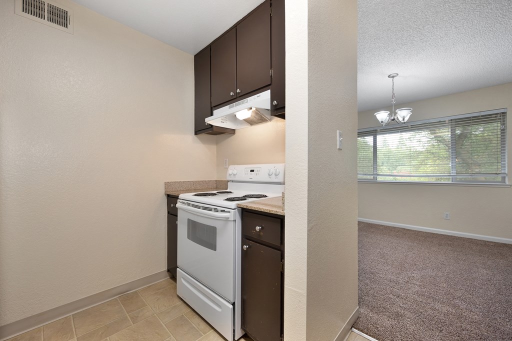 an empty kitchen with white appliances and a window