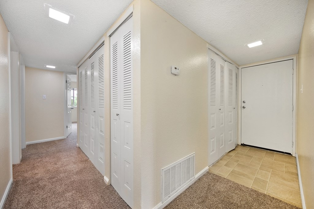 an empty room with white closets and a carpeted floor