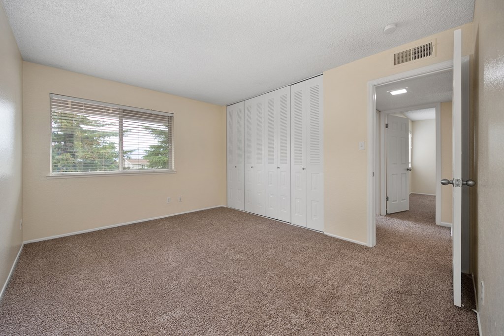 an empty living room with a window and a closet