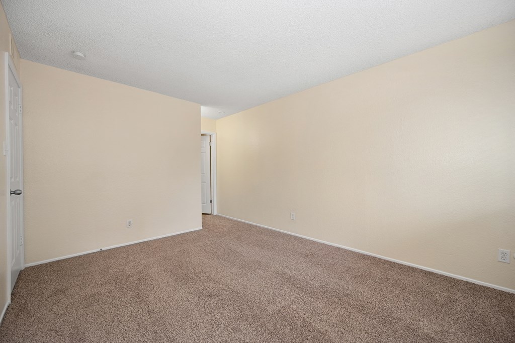 an empty living room with beige carpet and white walls