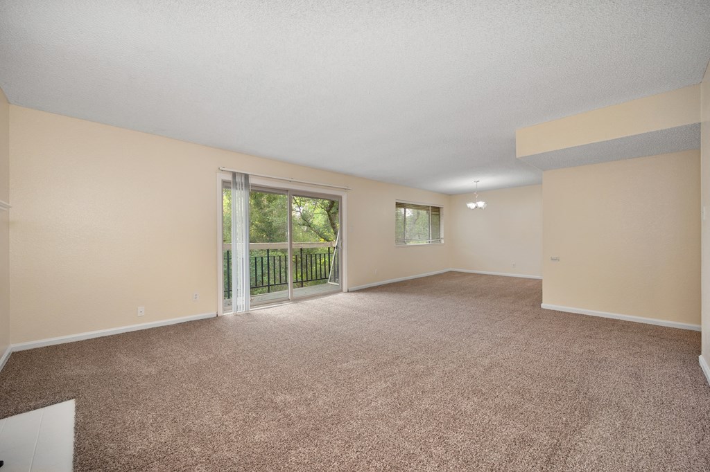 an empty living room with a sliding glass door to a balcony