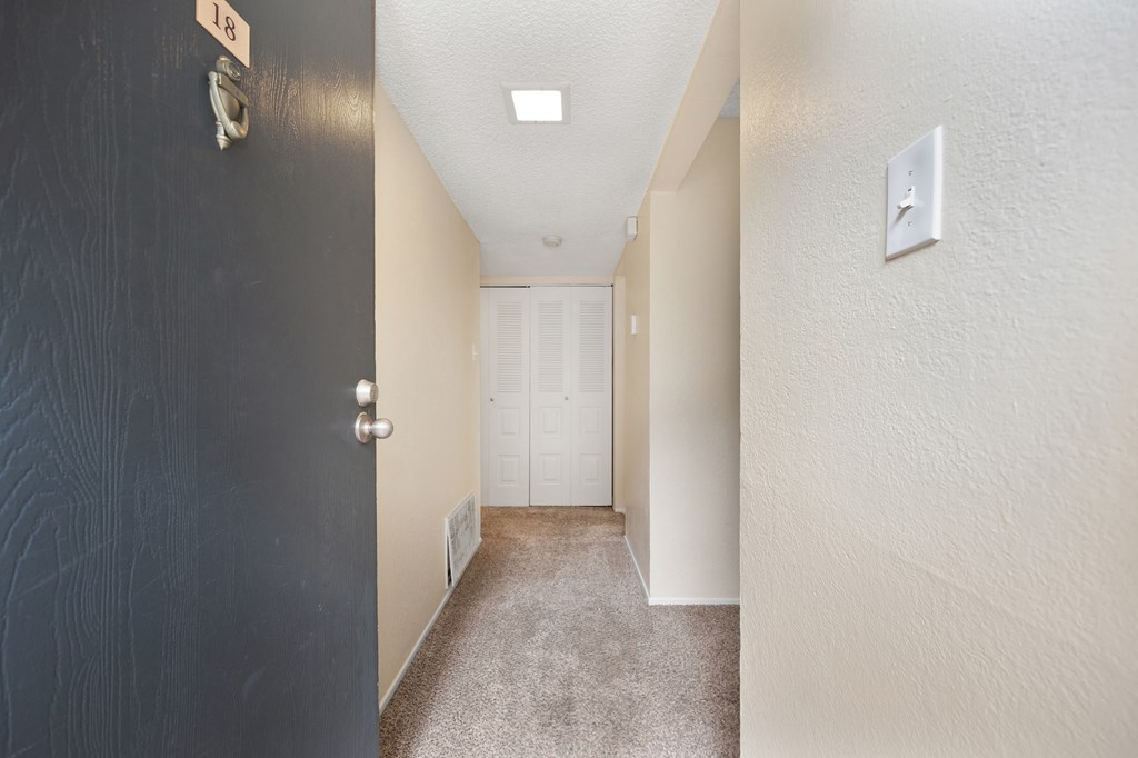 an open door leading to a hallway with a door to a closet
