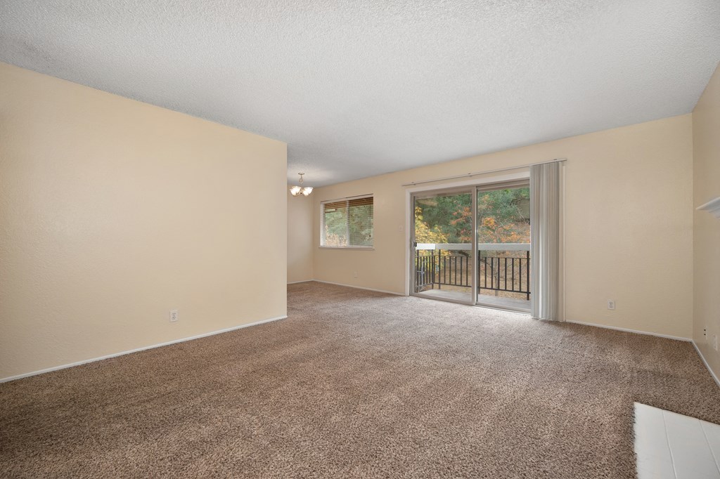 an empty living room with a sliding glass door to a balcony