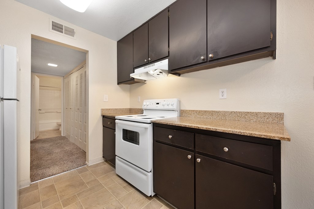 a kitchen with white appliances and a granite counter top and dark cabinets