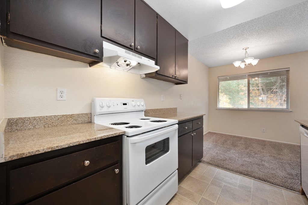 an empty kitchen with white appliances and dark cabinets