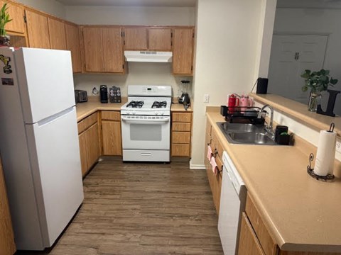 A kitchen with a white fridge, white stove, and wooden cabinets.