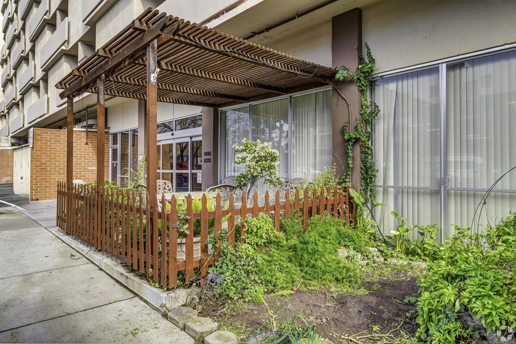 a house with a wooden fence and plants in front of it