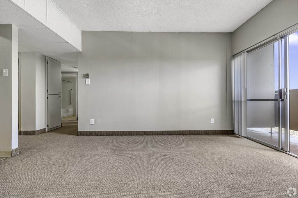 an empty living room with sliding glass doors to a hallway