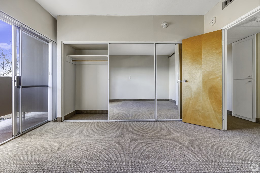 a empty room with mirrored doors and a door to a closet