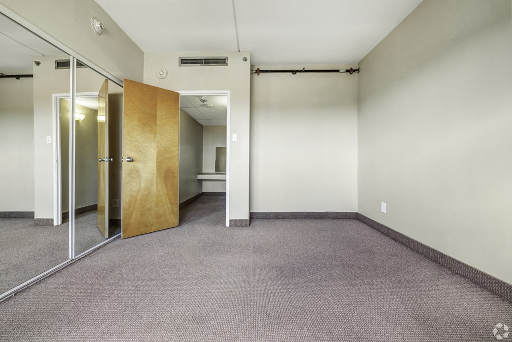 an empty room with a carpeted floor and mirrored doors