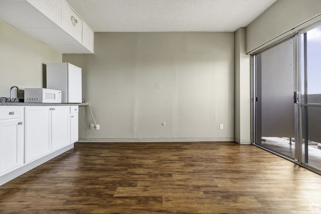 an empty kitchen with white cabinets and a stainless steel refrigerator