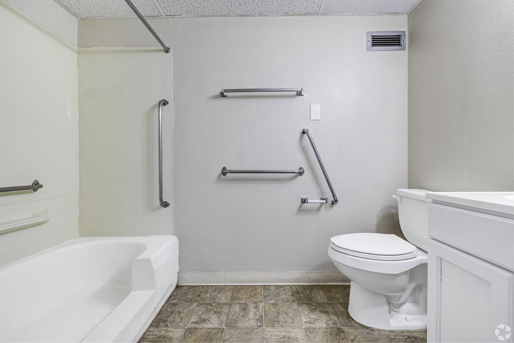 a bathroom with grab bars on the wall and a toilet and a tub