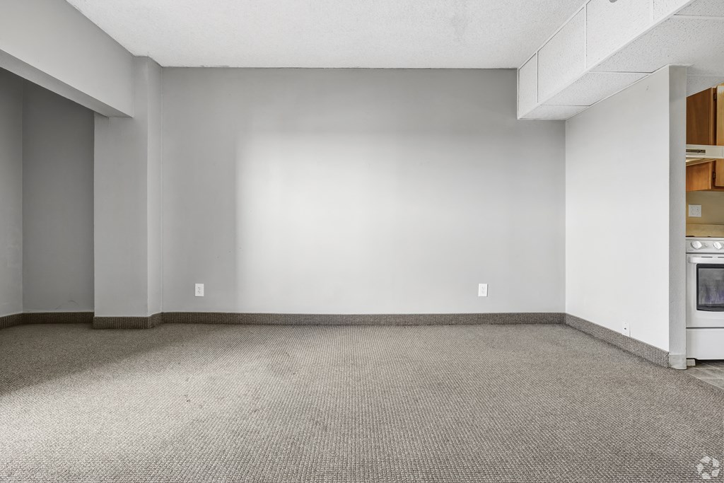 the living room of an empty house with a white wall and a stove
