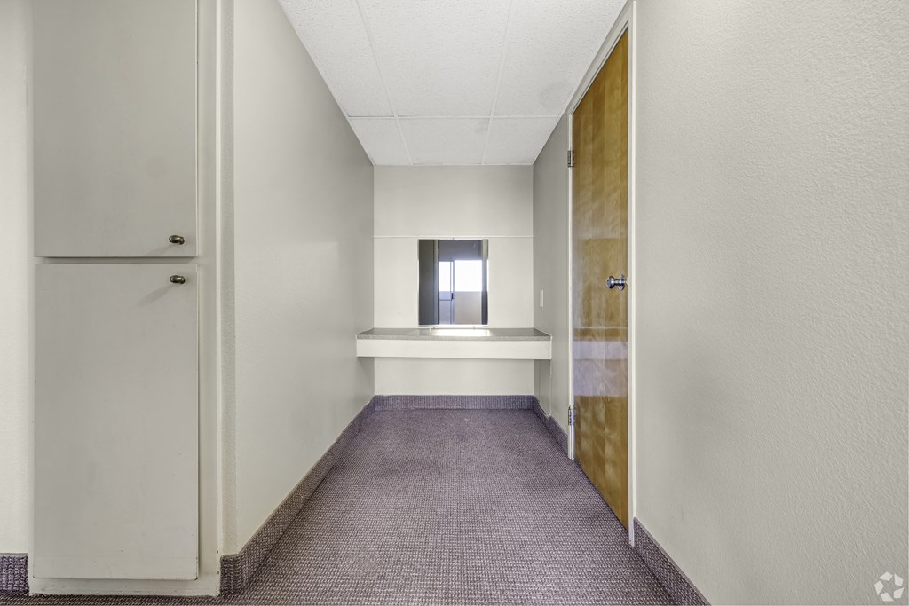 an empty hallway with a door to a room with a sink and a window