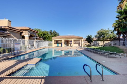 A large outdoor swimming pool with a diving board and a building in the background.