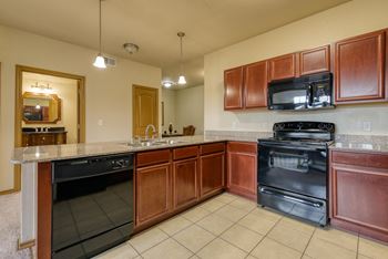 A kitchen with dark wood cabinets and black appliances.