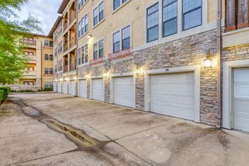 A row of garage doors are illuminated by lights on a building.