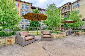 A patio with two chairs and an umbrella in front of a building.
