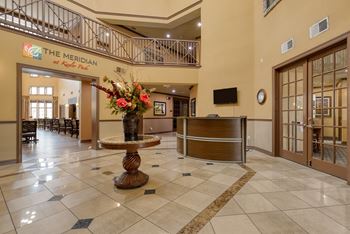 The lobby of The Meridian is shown with a large wooden table and chairs.