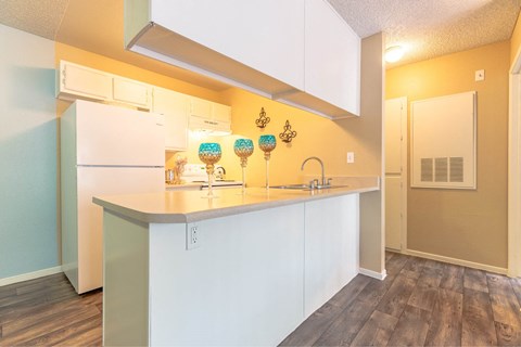 A kitchen with white cabinets and a white fridge.