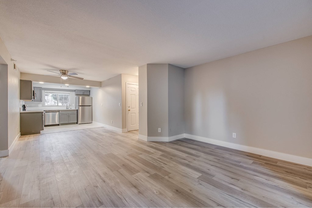 A spacious living room with a kitchen in the background.