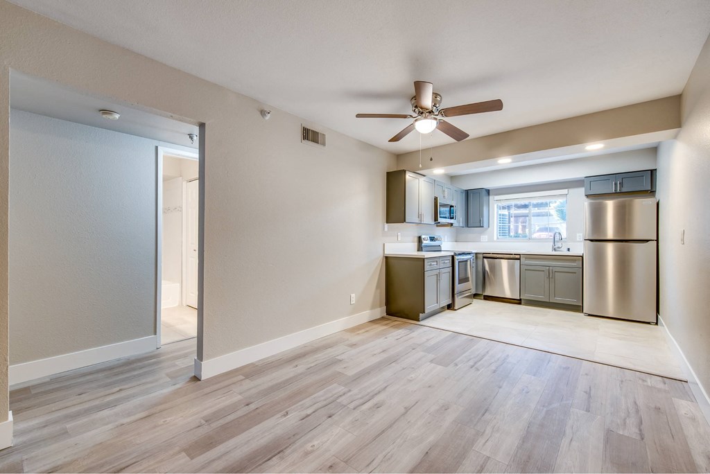 A kitchen with a refrigerator, microwave, and oven is visible from a living room.
