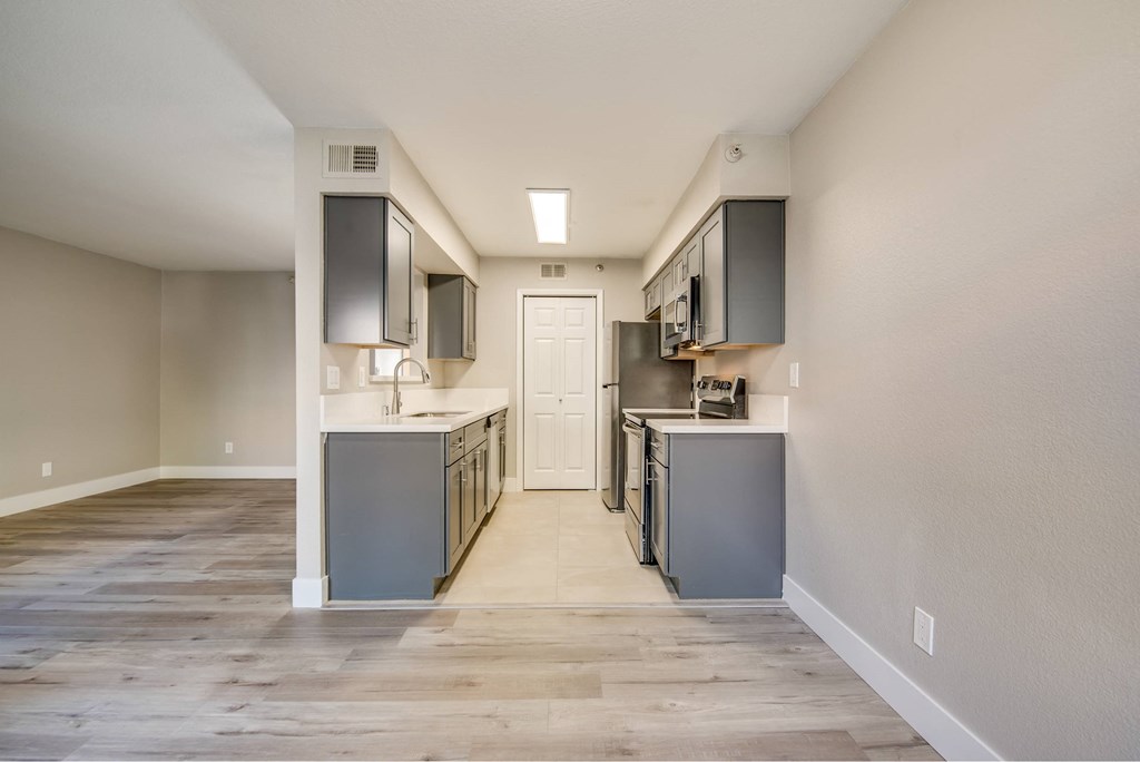 A kitchen with a white door in the middle of the room.