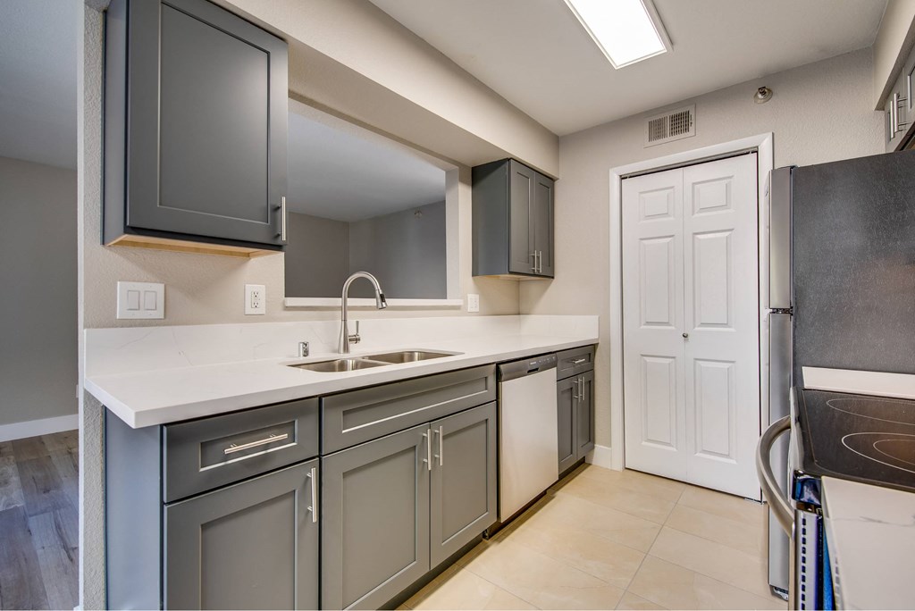 A modern kitchen with a white countertop and grey cabinets.