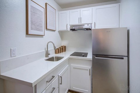 A kitchen with white cabinets and a stainless steel refrigerator.