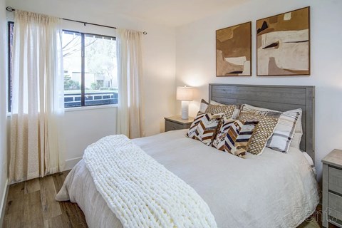 A bedroom with a large bed and two abstract paintings on the wall.