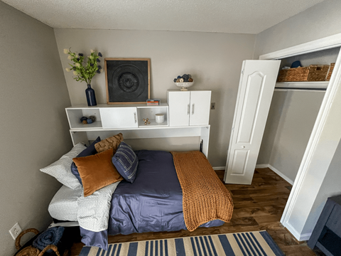 a bedroom with a bed and a shelf above it