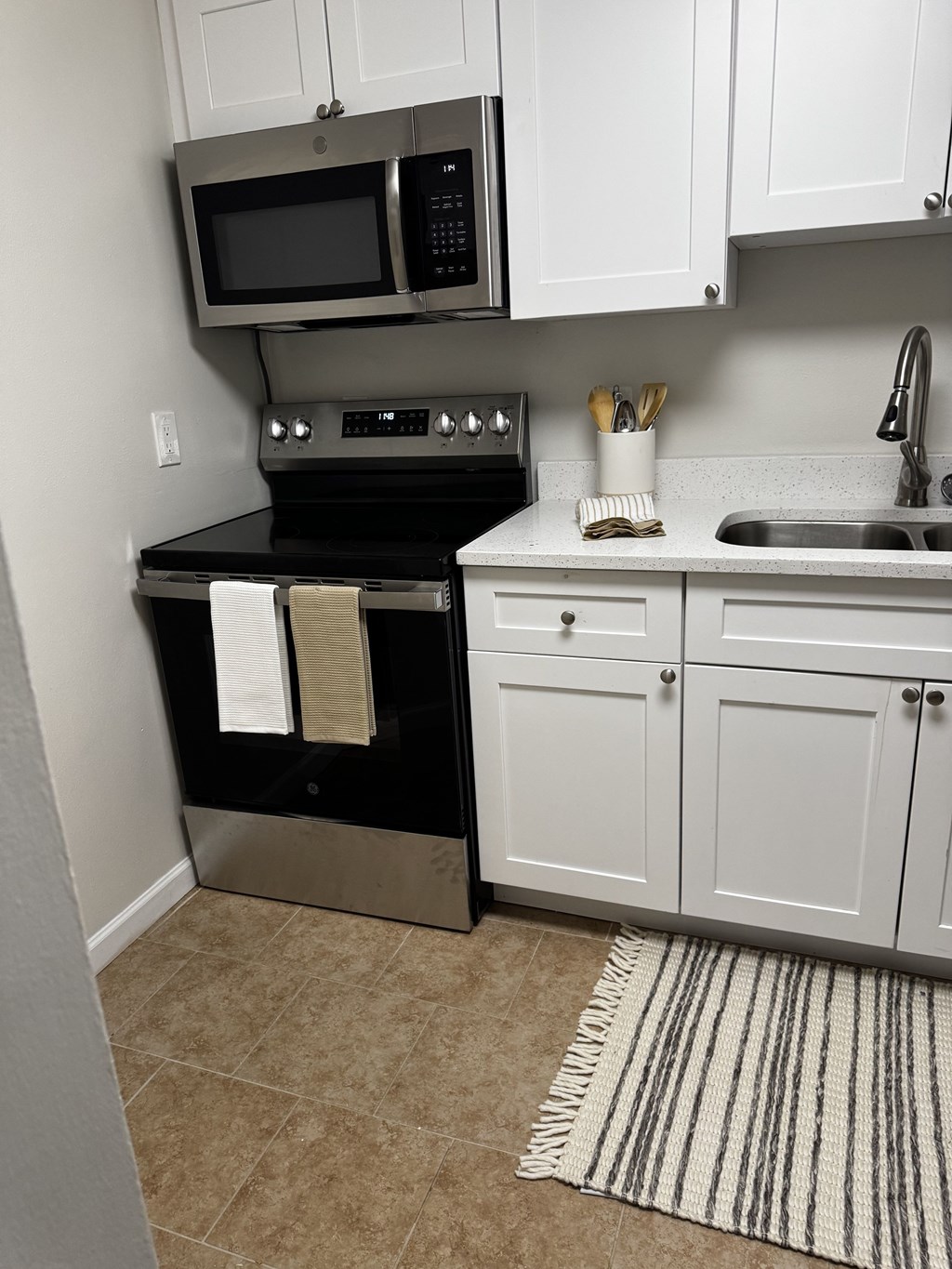 A kitchen with white cabinets and a black stove top oven.