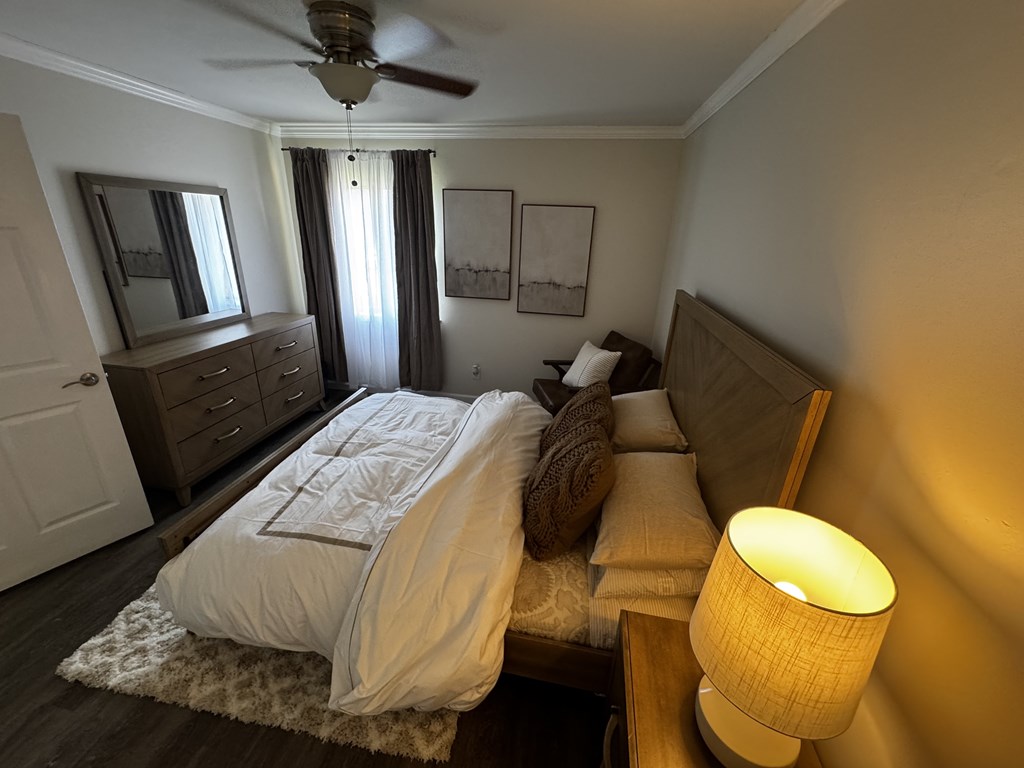 A bedroom with a bed, dresser, and ceiling fan.