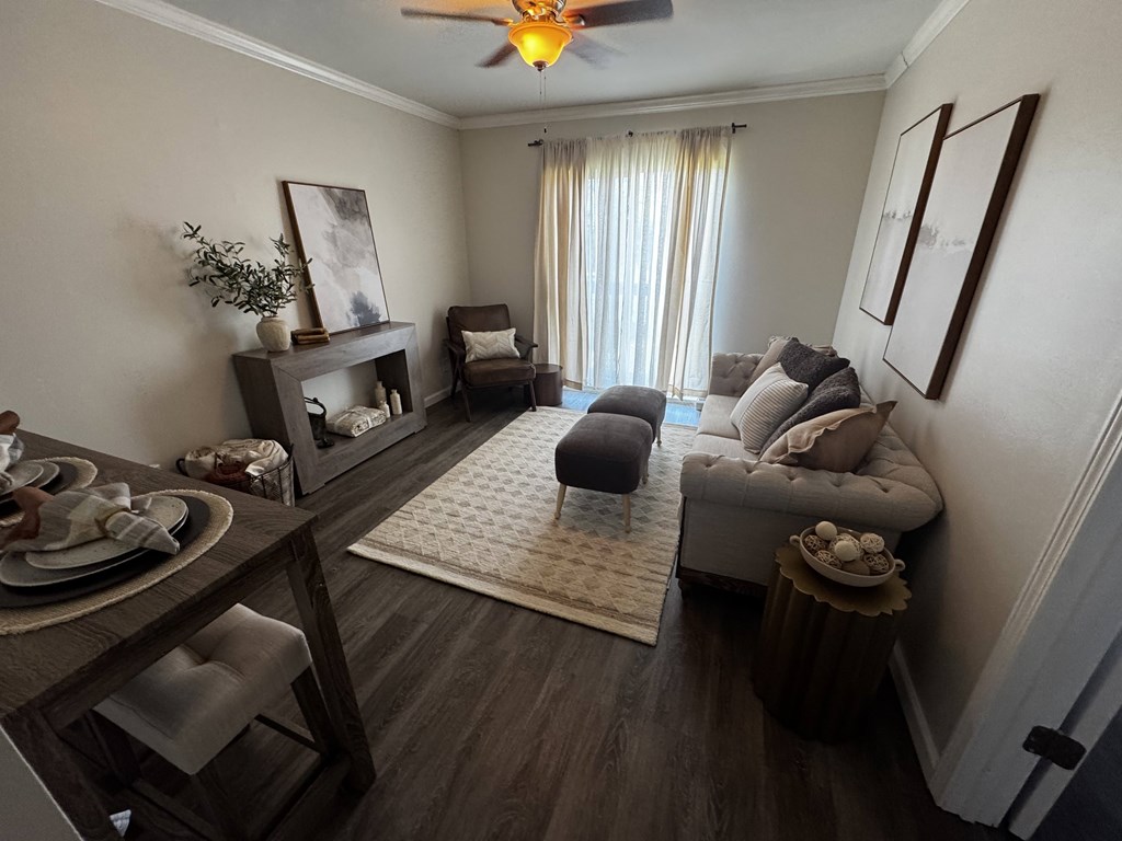 A living room with a grey couch, a wooden table, and a ceiling fan.