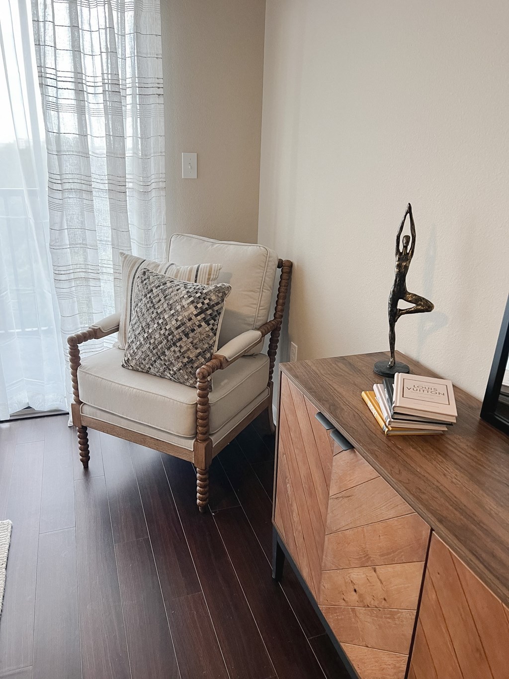 a living room with a chair and a dresser and a window