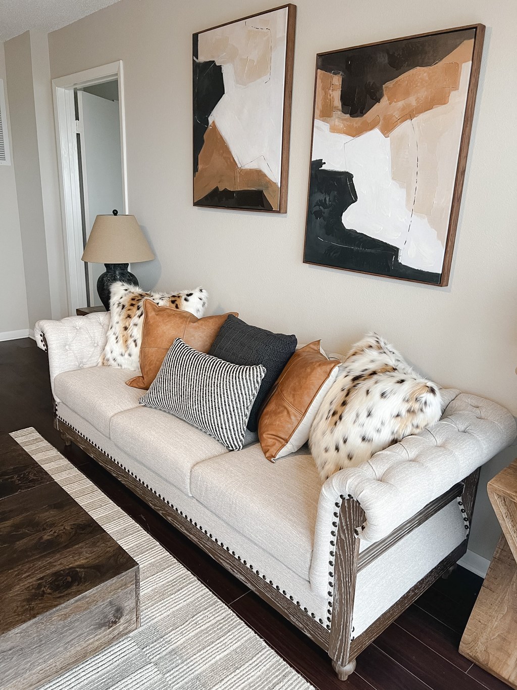 a living room with a couch with pillows and paintings on the wall