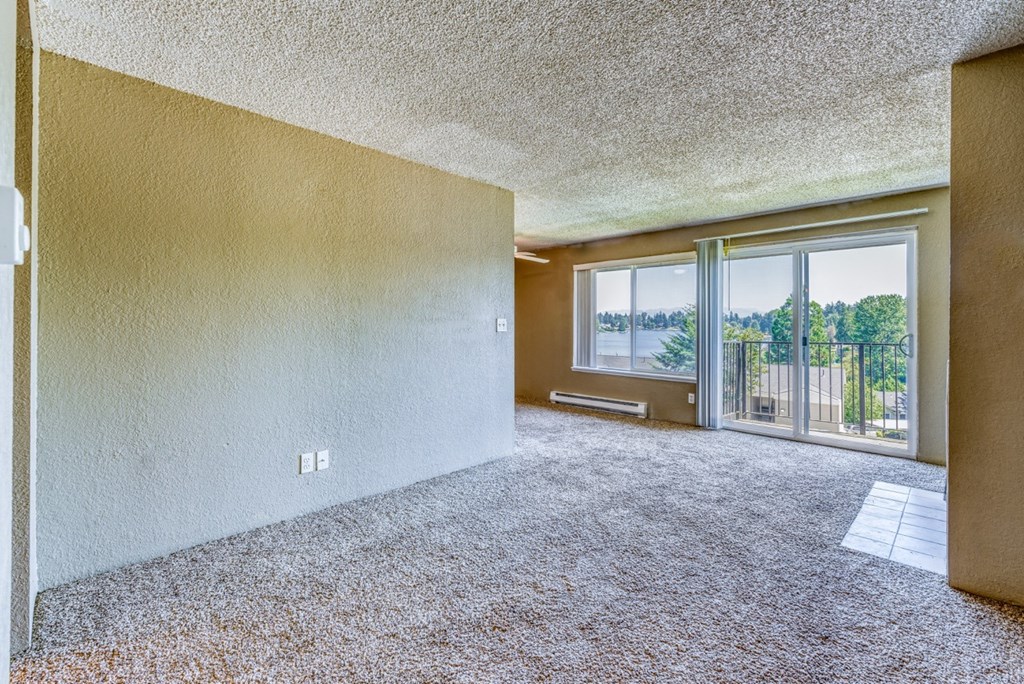 an empty living room with a balcony and a large window