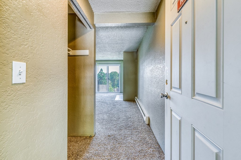 an empty hallway with a white door and a window