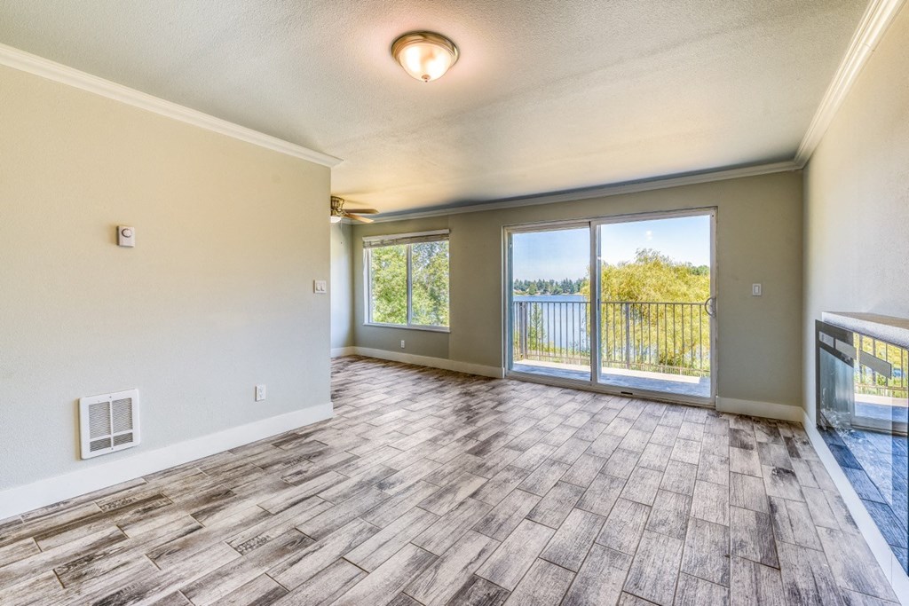 an empty living room with a sliding glass door to a balcony