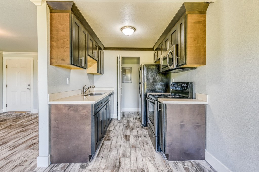 an empty kitchen with stainless steel appliances and wood flooring