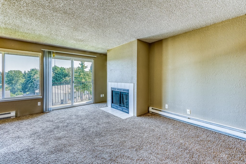 an empty living room with a fireplace and sliding glass doors