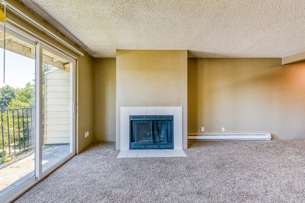 an empty living room with a fireplace and a sliding glass door