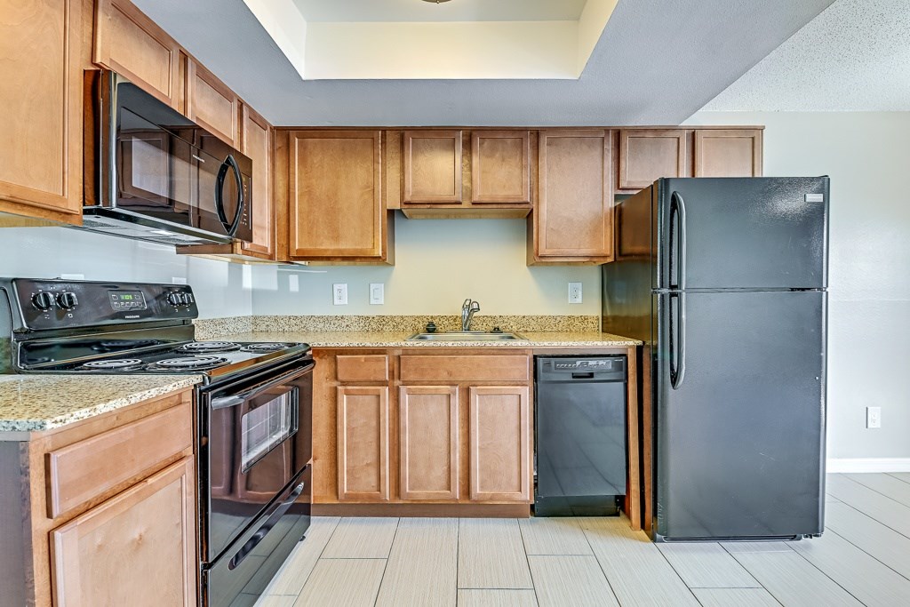 A kitchen with wooden cabinets and black appliances.