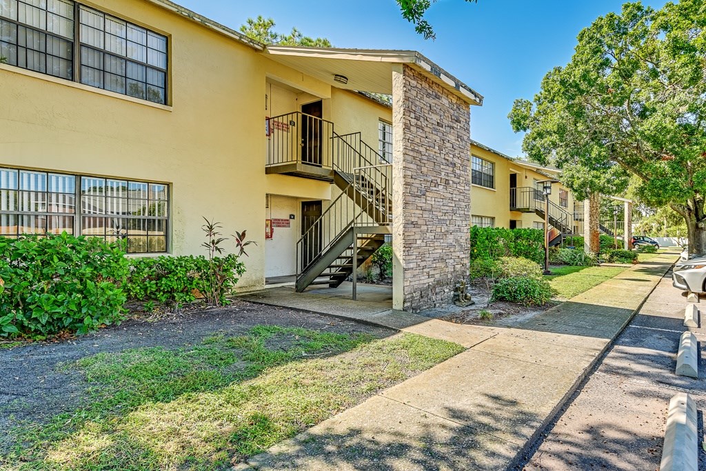 A yellow building with a balcony and a stone pillar.