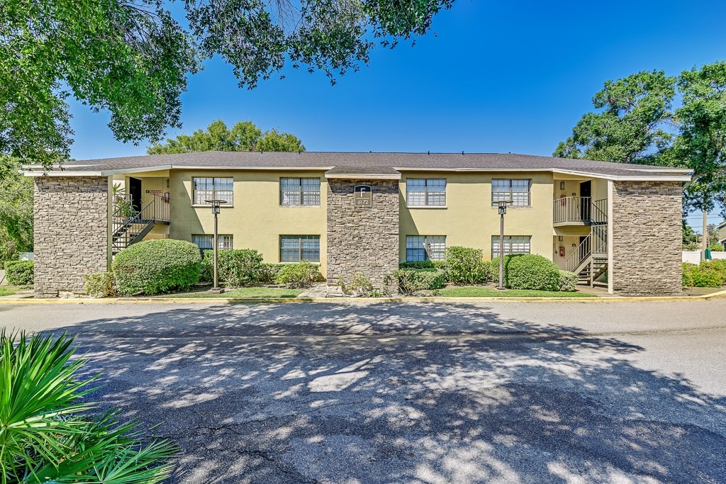 A sunny day at a stone and stucco apartment complex.