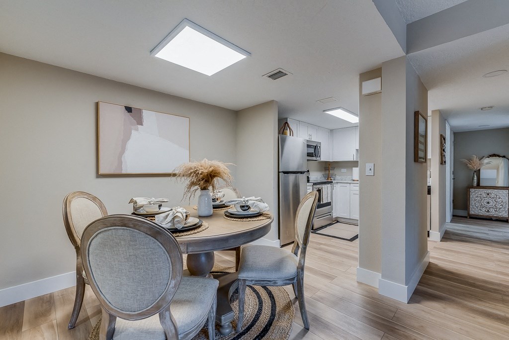 a dining area with a table and chairs and a kitchen in the background
