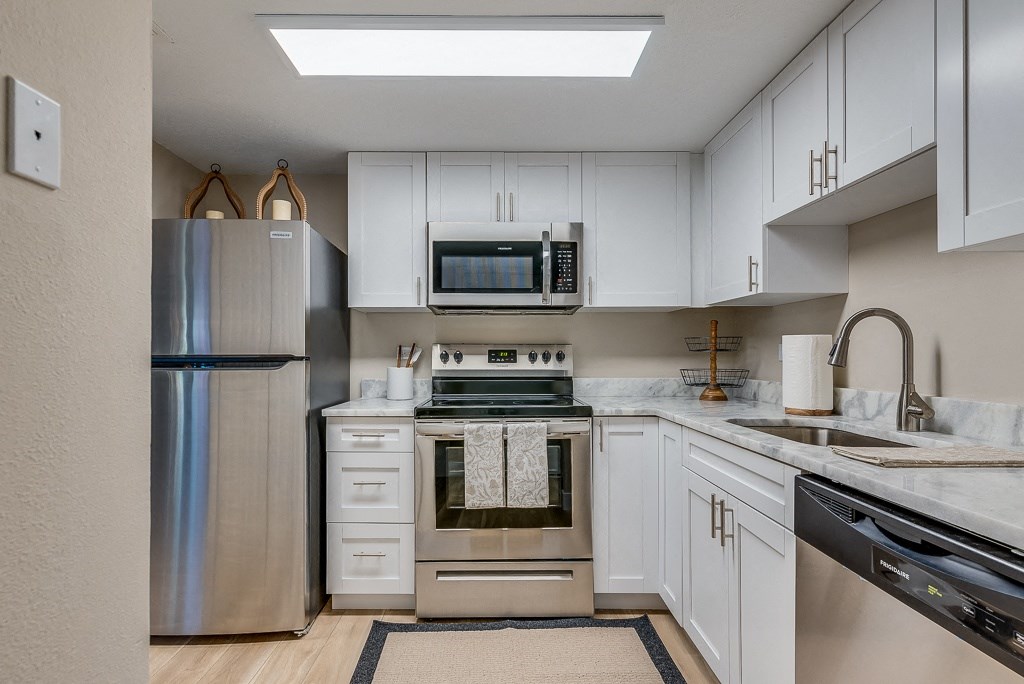 a kitchen with white cabinets and stainless steel appliances