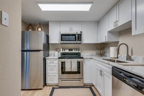 a kitchen with white cabinets and stainless steel appliances